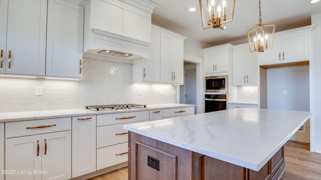 kitchen with stainless steel appliances, hanging light fixtures, a center island, and white cabinets