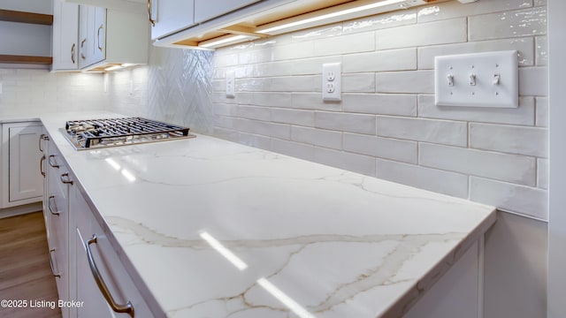 kitchen with tasteful backsplash, stainless steel gas stovetop, and light stone counters