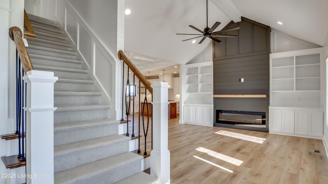 staircase with hardwood / wood-style flooring, ceiling fan, beam ceiling, and built in shelves