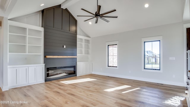 unfurnished living room with light hardwood / wood-style flooring, beam ceiling, a fireplace, and high vaulted ceiling