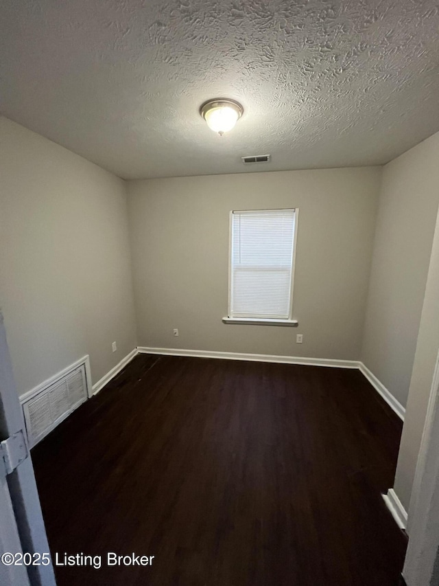 spare room with dark hardwood / wood-style floors and a textured ceiling