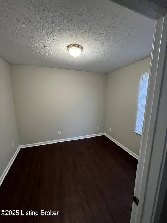 unfurnished room featuring dark wood-type flooring and a textured ceiling