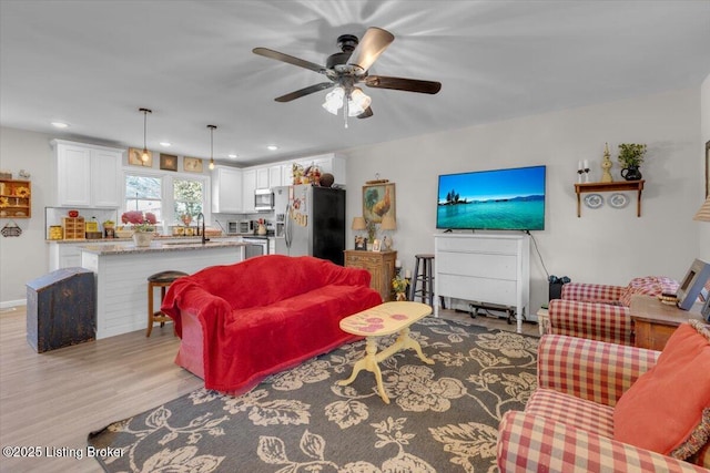 living room featuring ceiling fan, sink, and light hardwood / wood-style flooring