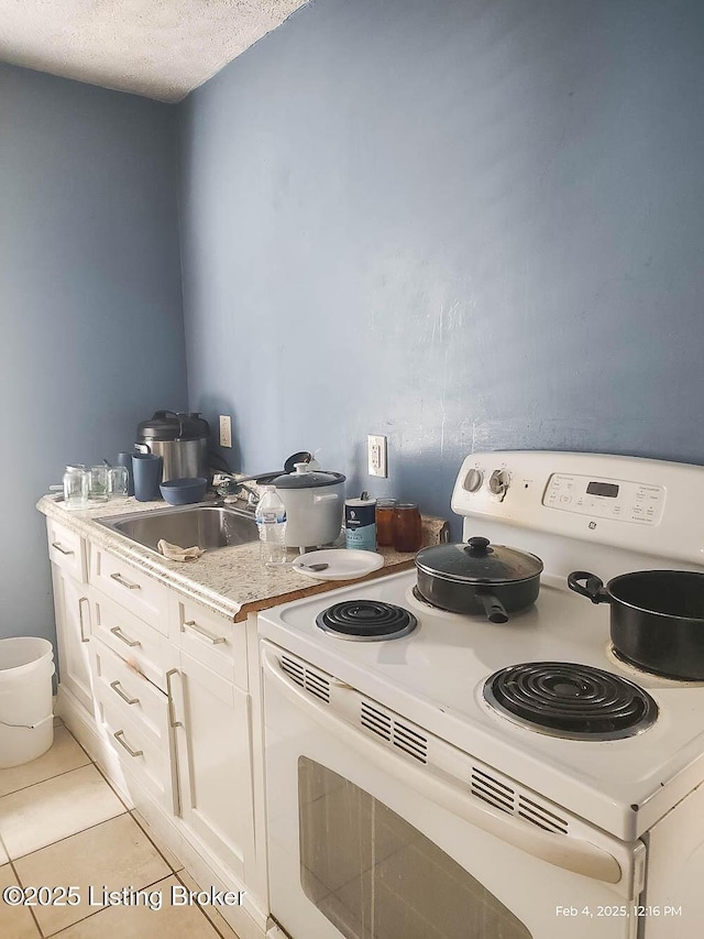 kitchen with white cabinetry, sink, light tile patterned floors, white range with electric cooktop, and a textured ceiling