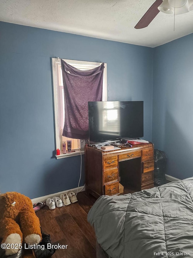 bedroom with ceiling fan, dark hardwood / wood-style floors, and a textured ceiling