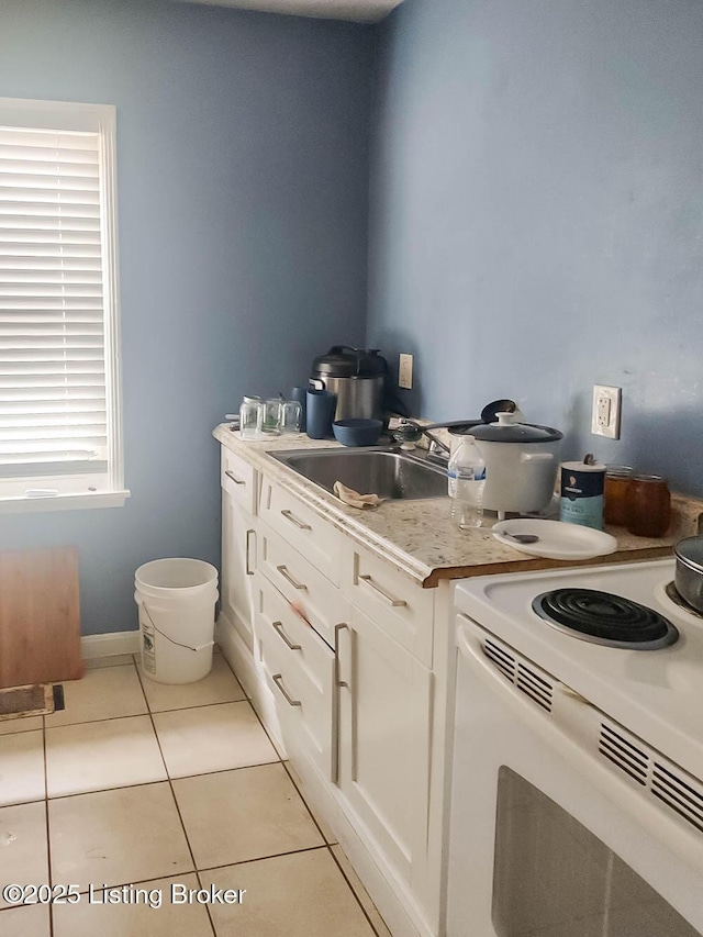 kitchen featuring white cabinetry, white range with electric cooktop, sink, and light tile patterned floors