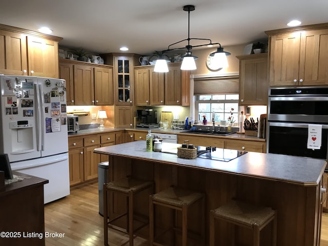 kitchen featuring pendant lighting, sink, black electric stovetop, white fridge with ice dispenser, and a kitchen island