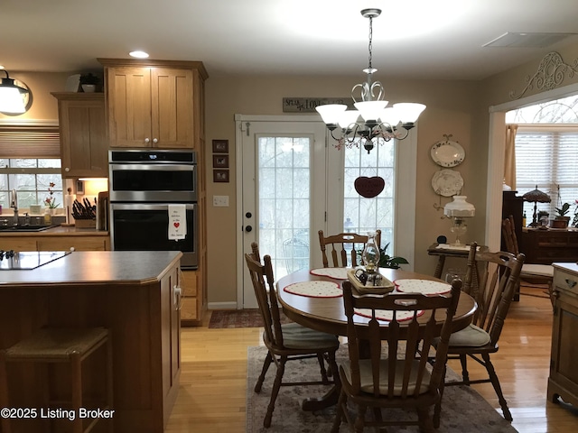 dining area with sink, an inviting chandelier, and light hardwood / wood-style floors