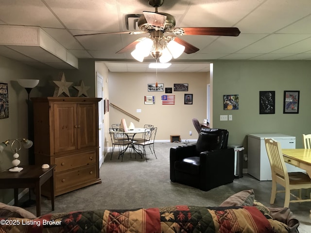 living room featuring carpet flooring, a drop ceiling, and ceiling fan