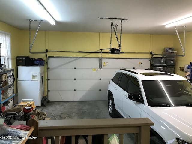 garage with a garage door opener and white refrigerator with ice dispenser