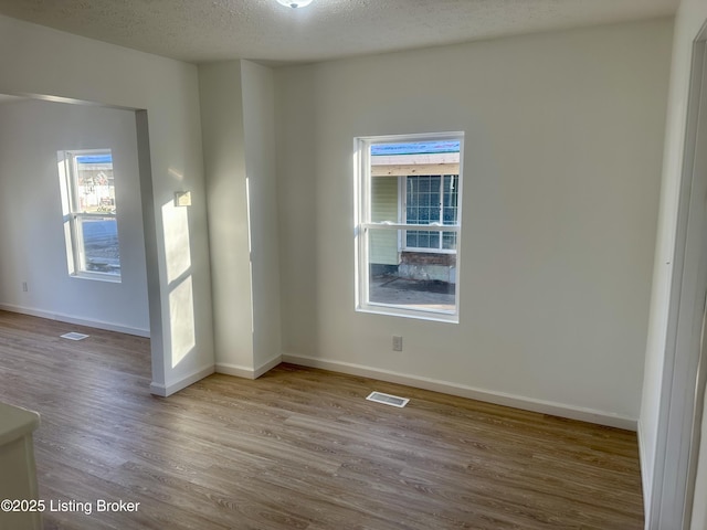 unfurnished room featuring a textured ceiling and light hardwood / wood-style flooring