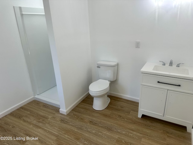 bathroom featuring walk in shower, vanity, toilet, and hardwood / wood-style floors