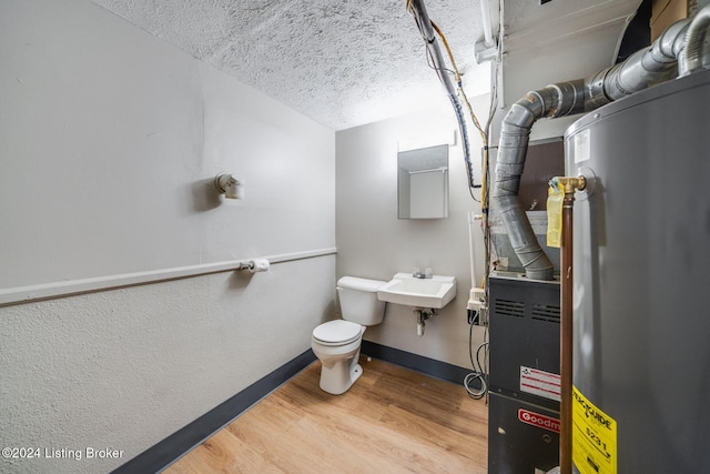 bathroom featuring toilet, sink, a textured ceiling, hardwood / wood-style flooring, and water heater