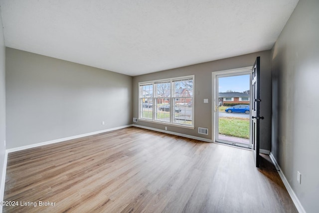 empty room with a textured ceiling and light wood-type flooring