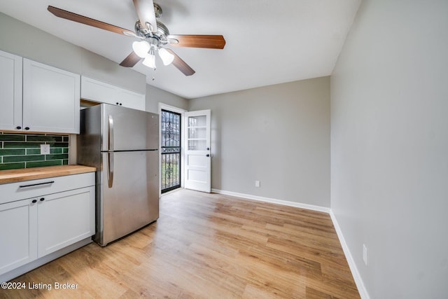 kitchen with white cabinets, tasteful backsplash, stainless steel fridge, and light hardwood / wood-style floors