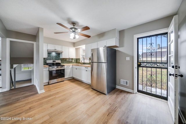 kitchen featuring sink, light hardwood / wood-style flooring, backsplash, stainless steel appliances, and white cabinets