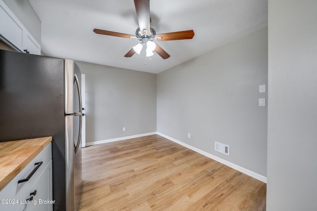 kitchen with stainless steel refrigerator, ceiling fan, light hardwood / wood-style flooring, and white cabinets