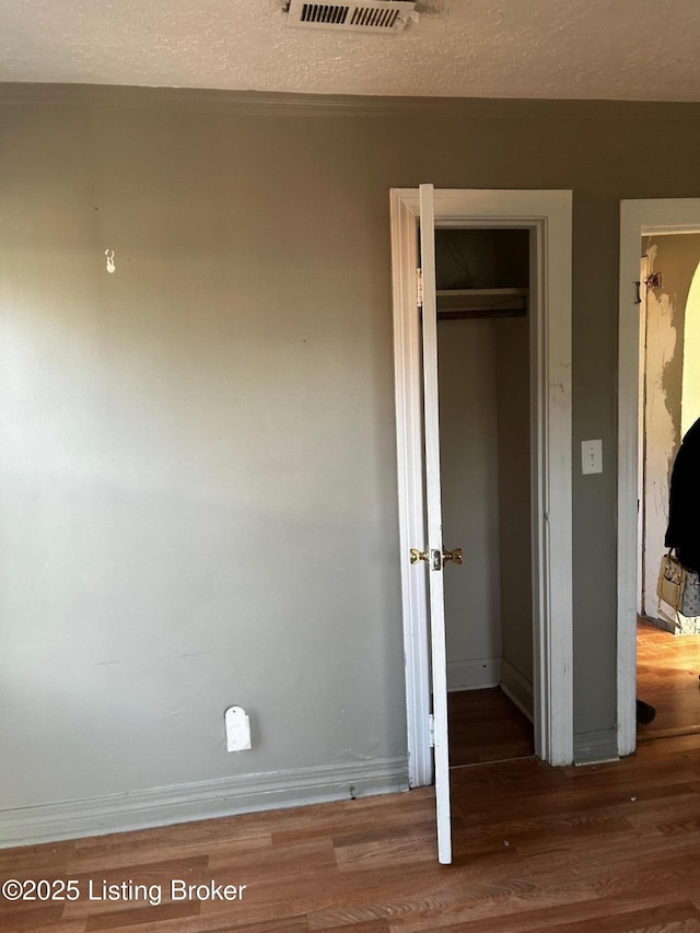 unfurnished bedroom with hardwood / wood-style flooring, a closet, and a textured ceiling