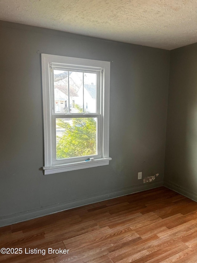 unfurnished room with a textured ceiling and light wood-type flooring