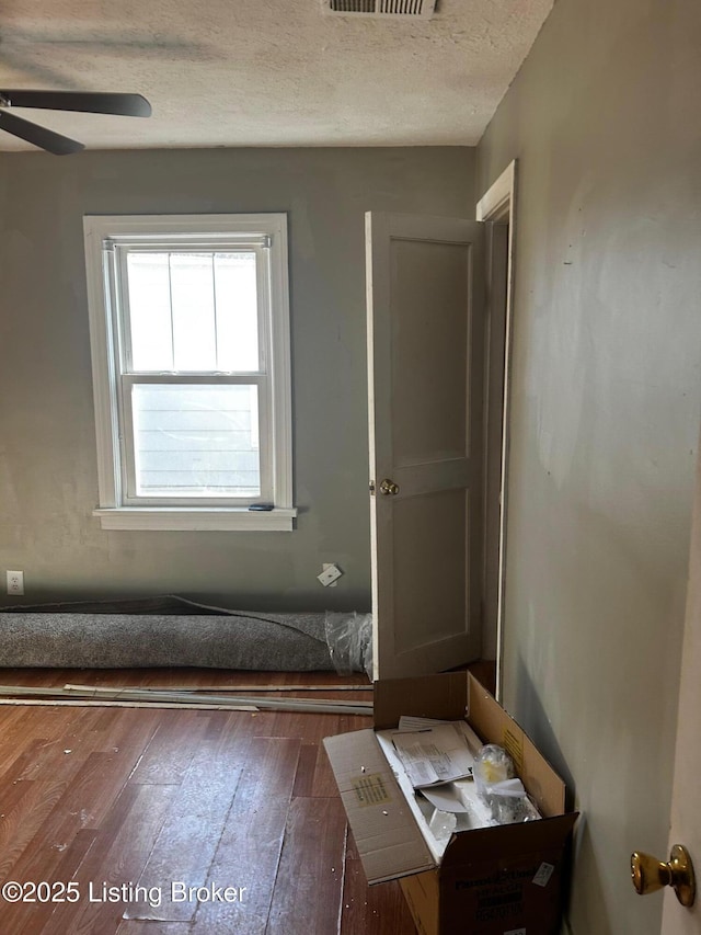 interior space with ceiling fan, dark wood-type flooring, and a textured ceiling