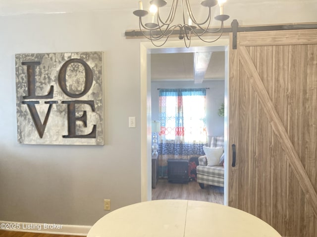 dining room featuring dark wood-type flooring, a barn door, and a chandelier