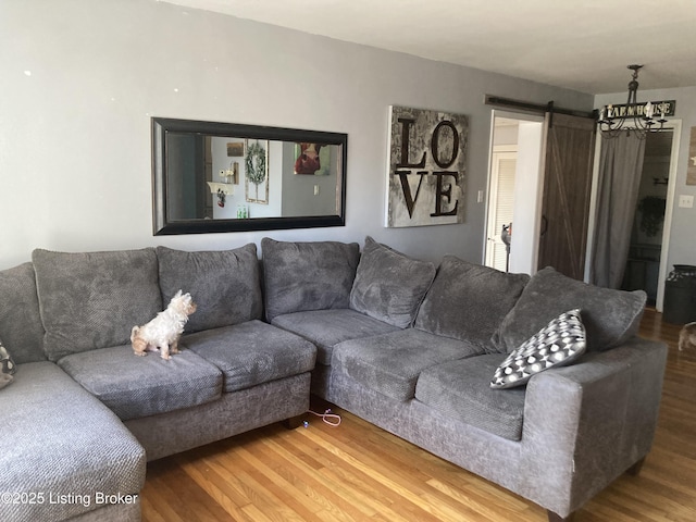 living room with a barn door and wood finished floors