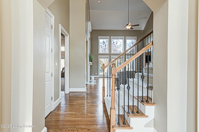 foyer featuring ceiling fan, stairway, baseboards, and wood finished floors