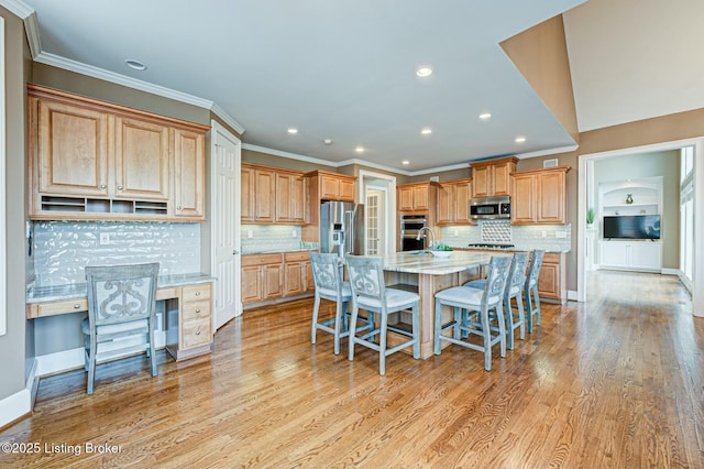 kitchen with light wood finished floors, a kitchen bar, a kitchen island with sink, and stainless steel appliances