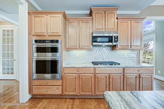 kitchen with light stone counters, stainless steel appliances, light wood-style floors, tasteful backsplash, and crown molding