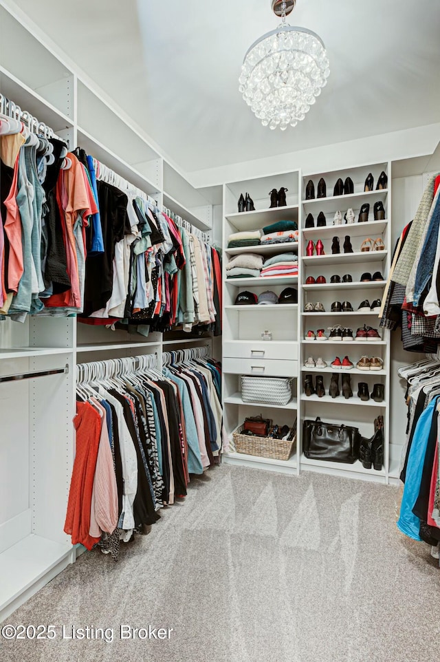 walk in closet with a notable chandelier and carpet flooring