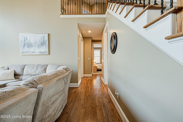 corridor with a towering ceiling, baseboards, stairway, and dark wood finished floors