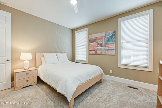 bedroom featuring light carpet, multiple windows, visible vents, and baseboards