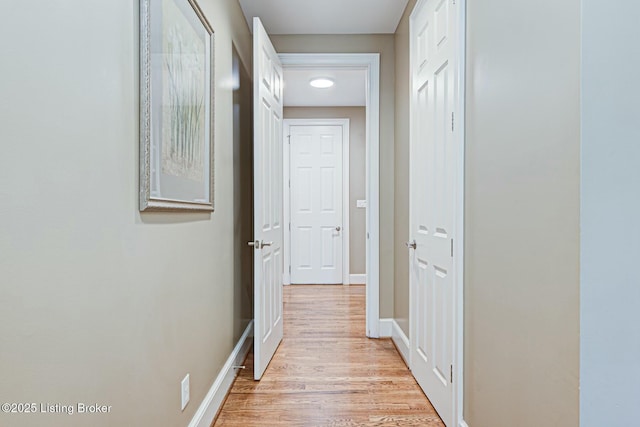 hall featuring light wood-style flooring and baseboards