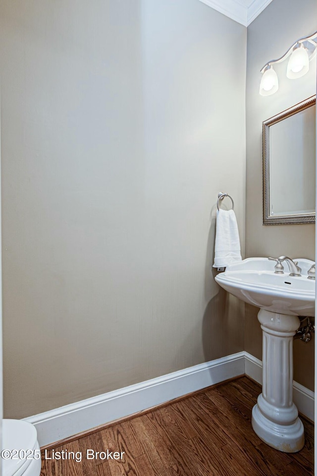 bathroom featuring ornamental molding, toilet, baseboards, and wood finished floors