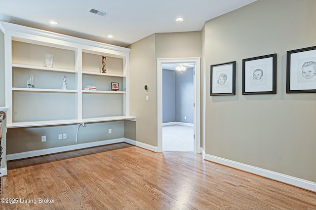 empty room with built in features, recessed lighting, visible vents, wood finished floors, and baseboards