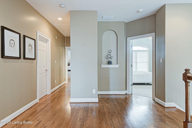 hallway with recessed lighting, wood finished floors, visible vents, baseboards, and attic access