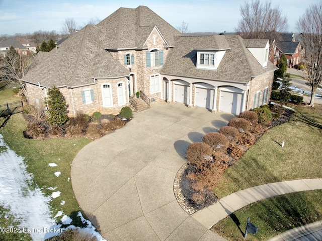 french provincial home with an attached garage, a shingled roof, concrete driveway, stone siding, and a front lawn