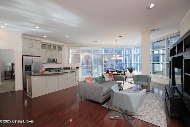 living room featuring plenty of natural light, dark hardwood / wood-style floors, a chandelier, and sink