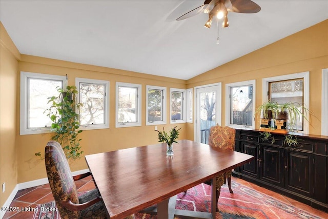 tiled dining space with ceiling fan and vaulted ceiling