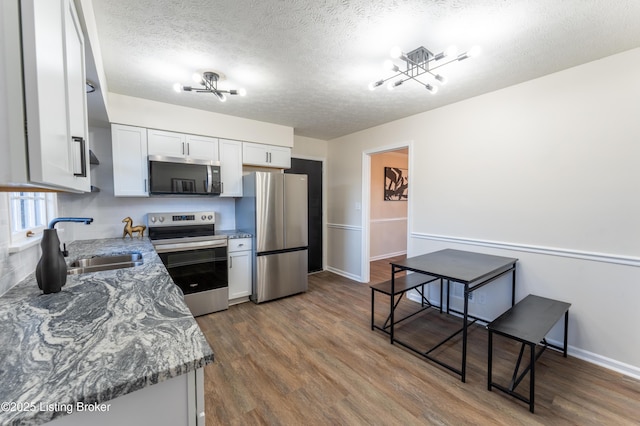 kitchen featuring sink, white cabinets, dark hardwood / wood-style flooring, light stone counters, and stainless steel appliances