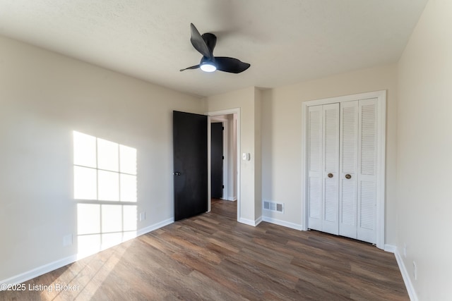 unfurnished bedroom featuring ceiling fan, dark hardwood / wood-style flooring, and a closet