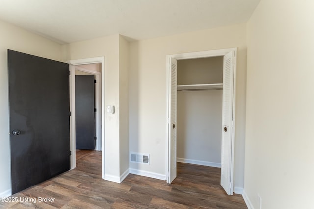 unfurnished bedroom featuring dark wood-type flooring and a closet