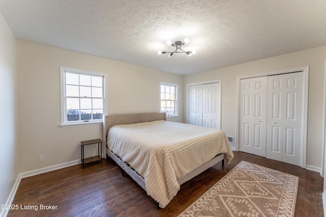 bedroom featuring multiple closets, dark hardwood / wood-style floors, and a textured ceiling