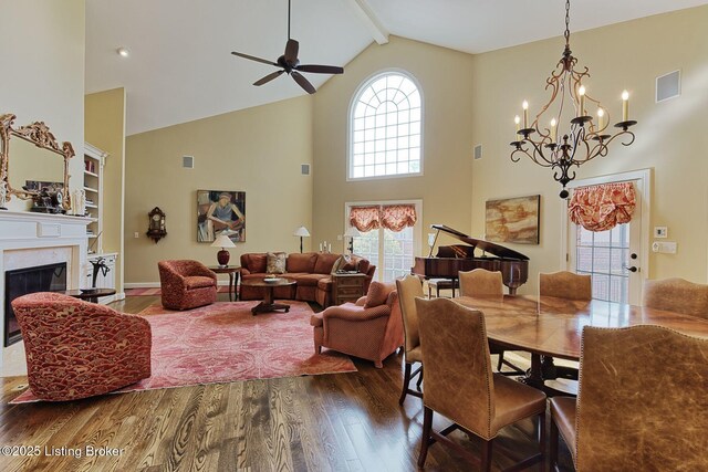 dining space with ceiling fan, a fireplace, visible vents, dark wood-style floors, and beamed ceiling