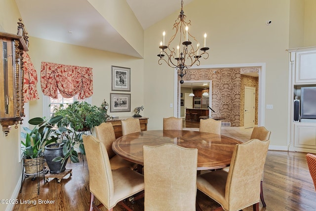 dining area with high vaulted ceiling, a notable chandelier, baseboards, and wood finished floors