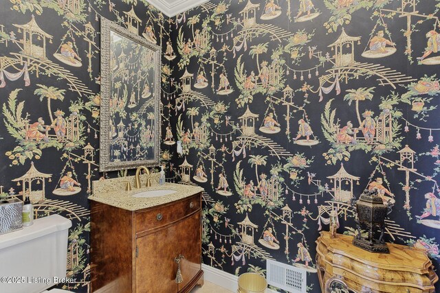 half bath with toilet, visible vents, ornamental molding, and vanity