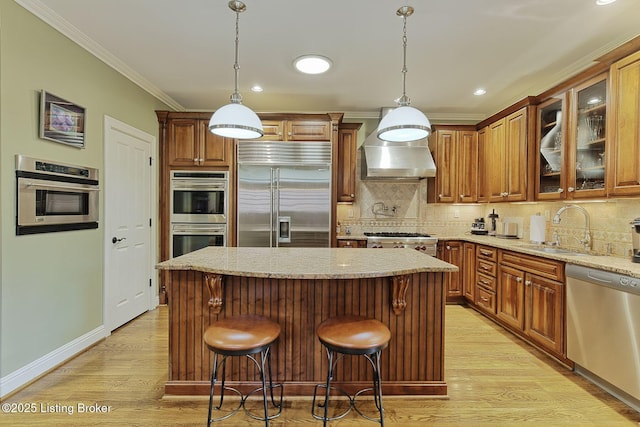 kitchen with stainless steel appliances, crown molding, a sink, and light wood finished floors