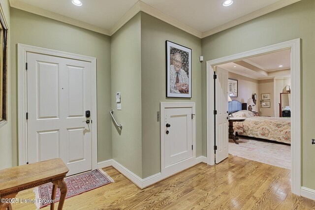 foyer with light wood finished floors, baseboards, and ornamental molding