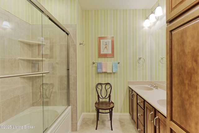 bathroom featuring tile patterned flooring, a sink, combined bath / shower with glass door, double vanity, and wallpapered walls