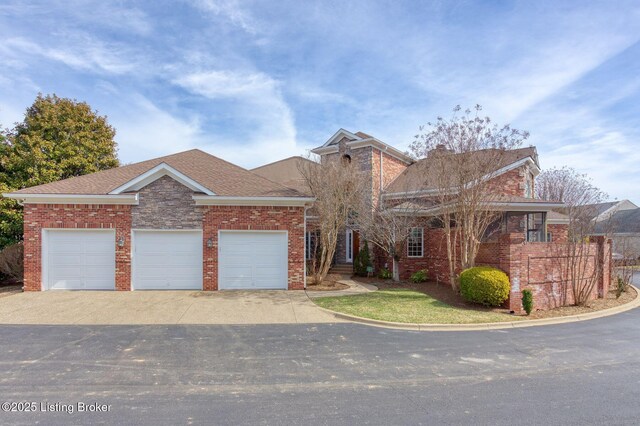 view of front of home featuring brick siding, driveway, an attached garage, and roof with shingles